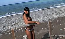 Uma adolescente morena boba com seios enormes e falsos posa na praia