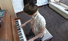 Игрива брюнетка с нахални цици свири на пиано без горнище