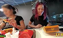 Két szexuálisan izgatott nő mellei ki vannak téve, miközben McDonalds-ban étkeznek - egy profi módon tintával ellátott angyallal